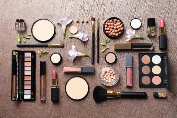Muitos produtos de maquiagem diferentes e flores de primavera no fundo de cor, flat lay — Fotografia de Stock