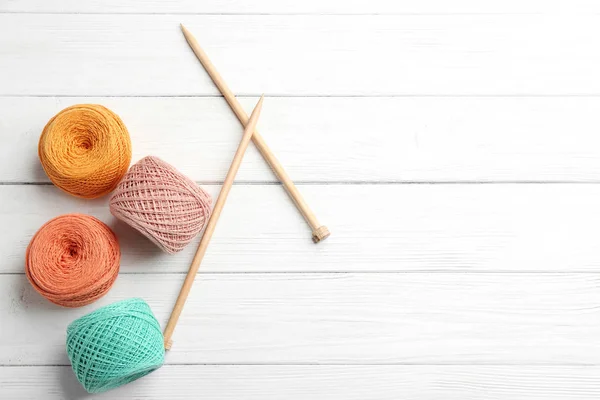 Clews of threads and knitting needles on wooden table, flat lay with space for text. Sewing stuff — Stock Photo, Image