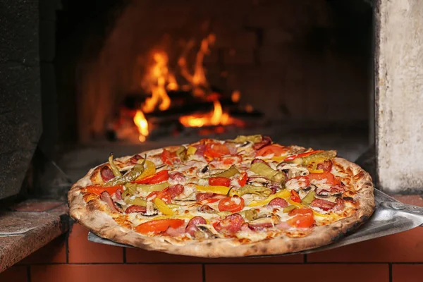 Ta välsmakande pizza ur ugnen i restaurangkök — Stockfoto