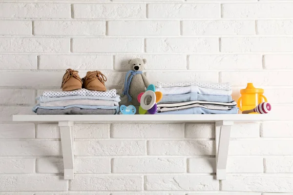 Plank met baby accessoires op witte bakstenen muur — Stockfoto