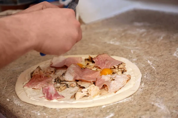 Ο άνθρωπος ετοιμάζει πίτσα στο τραπέζι, κοντινό. Συνταγή φούρνου — Φωτογραφία Αρχείου