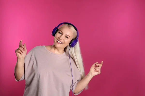 Ώριμη γυναίκα που απολαμβάνει μουσική στα ακουστικά στο χρώμα φόντο. Χώρος για κείμενο — Φωτογραφία Αρχείου