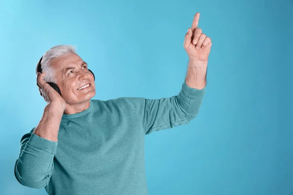 Mature man enjoying music in headphones on color background — Stock Photo, Image