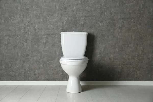 Neue Toilettenschüssel in der Nähe grauer Wände — Stockfoto