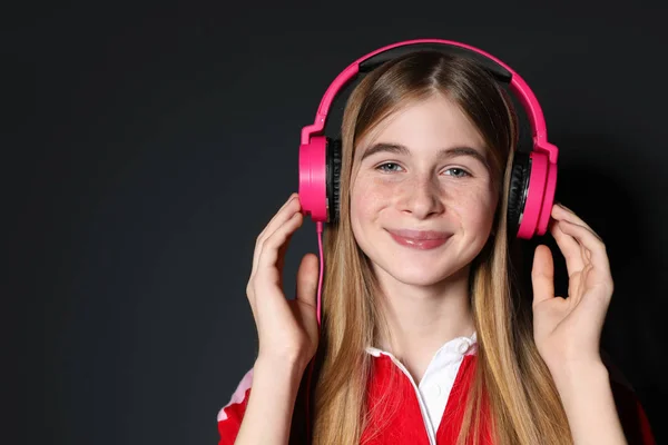 Adolescente disfrutando de la música en los auriculares sobre fondo negro. Espacio para texto —  Fotos de Stock