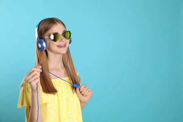 Έφηβο κορίτσι που απολαμβάνει μουσική στα ακουστικά σε χρώμα φόντου. Χώρος για κείμενο — Φωτογραφία Αρχείου