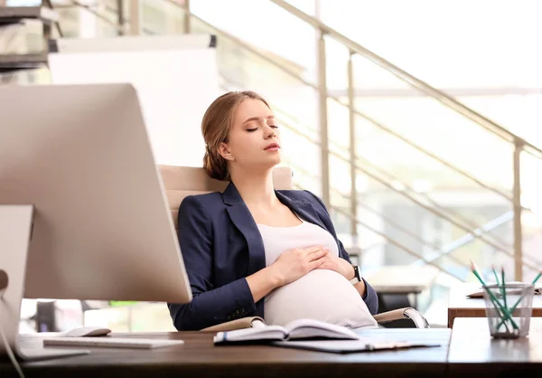 Młoda kobieta w ciąży cierpiąca na ból podczas pracy w biurze — Zdjęcie stockowe