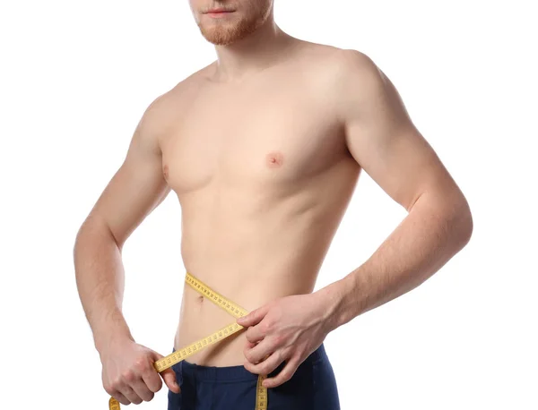 Молодой человек с измерительной лентой показывает свое стройное тело на белом фоне, крупным планом — стоковое фото