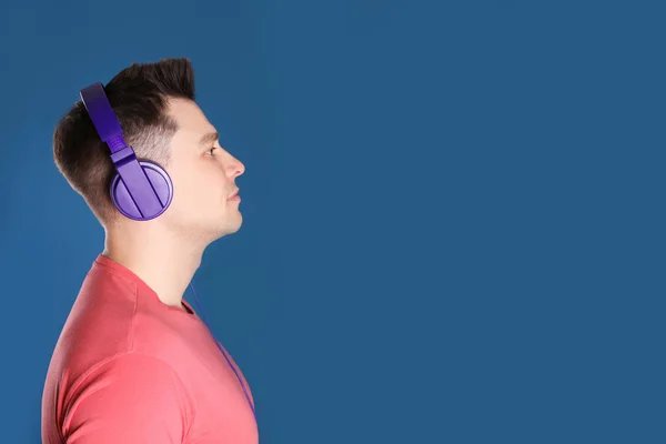 Homem desfrutando de música em fones de ouvido no fundo de cor. Espaço para texto — Fotografia de Stock