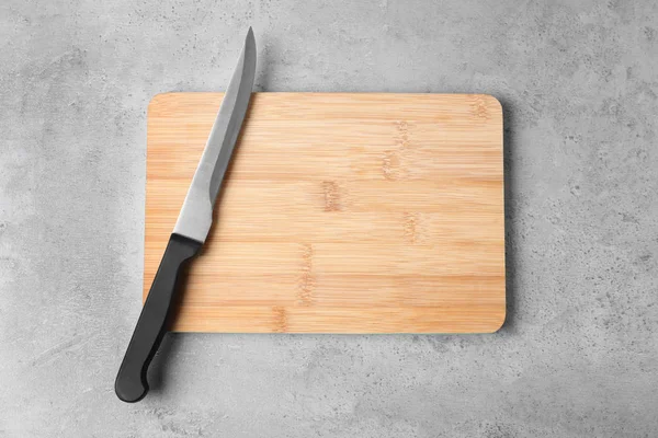 Tabla de cortar con cuchillo sobre fondo gris, plano. Espacio para texto — Foto de Stock