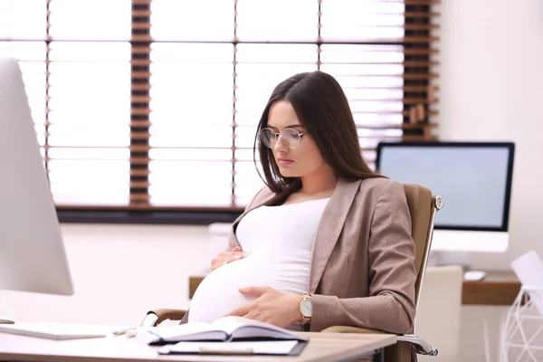 Jeune femme enceinte souffrant de douleur pendant qu'elle travaille au bureau — Photo