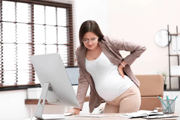 Jovem grávida sofrendo de dor enquanto trabalhava no escritório — Fotografia de Stock