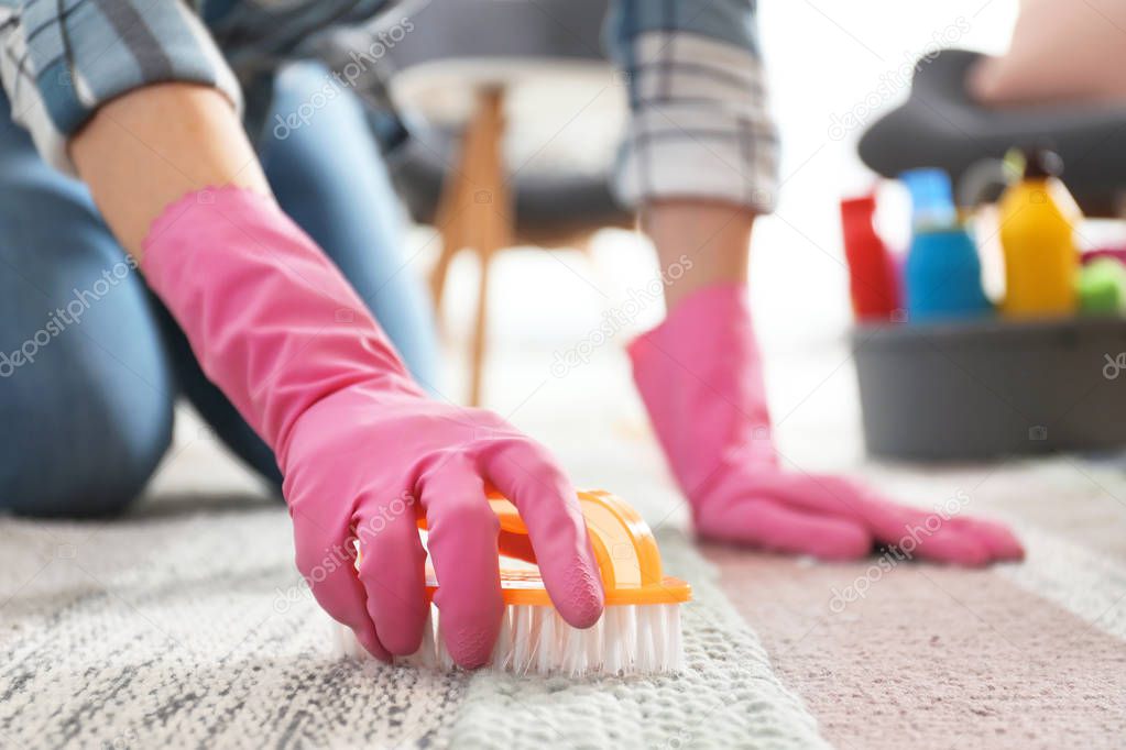 Woman cleaning carpet with brush in living room, closeup