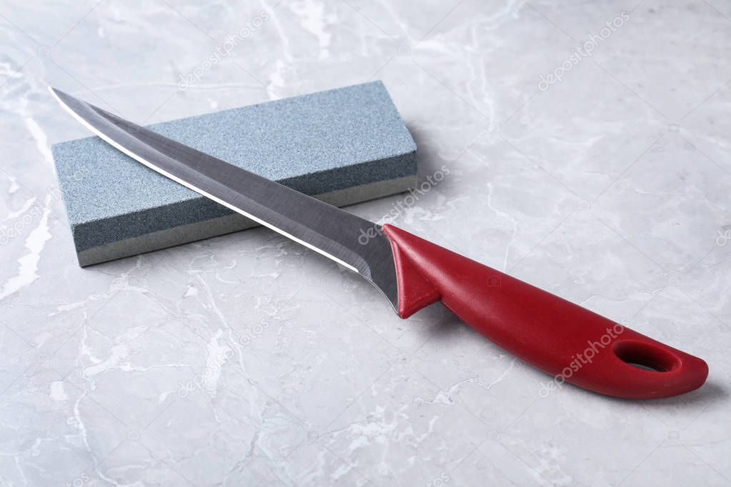 Boning knife and sharpening stone on grey background