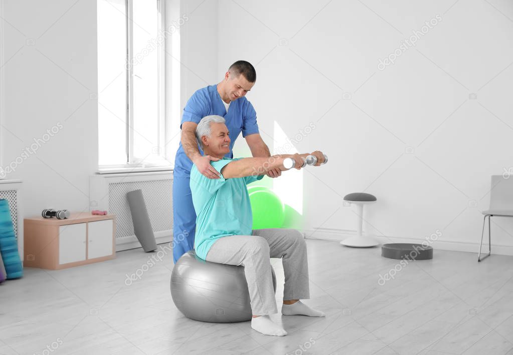 Professional physiotherapist working with senior patient in rehabilitation center