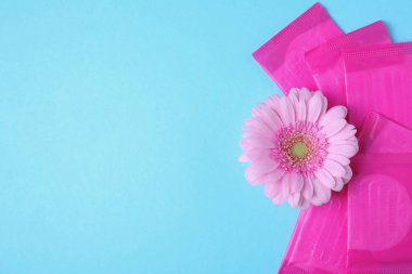 Paketlenmiş adet pedleri ve renk arka plan üzerinde çiçek, düz metin için boşluk yatıyordu. Jinekolojik bakım