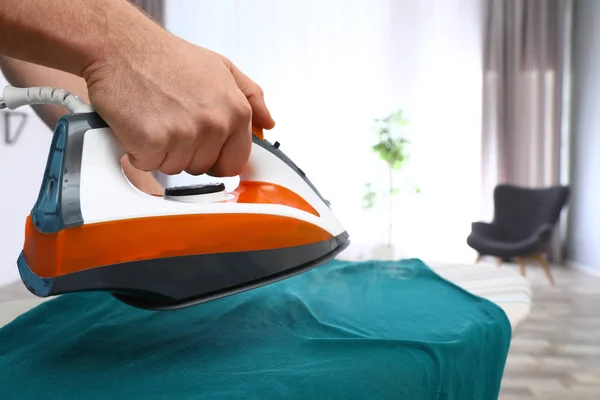 Man ironing clothes on board at home, closeup — Stock Photo, Image