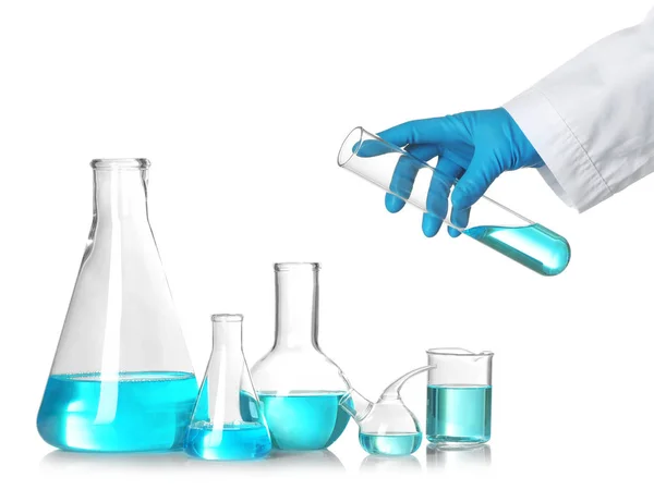 Wetenschapper Holding reageerbuis over tafel met laboratorium glaswerk tegen witte achtergrond. Chemisch onderzoek — Stockfoto
