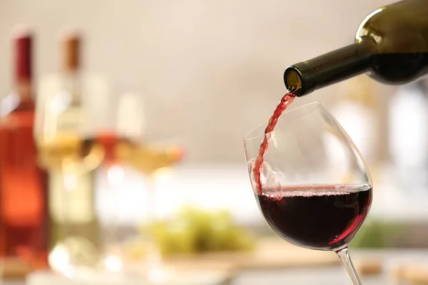 Наливаючи червоне вино з пляшки в склянку на розмитому фоні. Простір для тексту — стокове фото