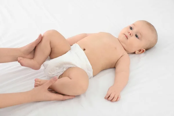 Moeder en haar schattige kind op wit bed. Baby massage en oefeningen — Stockfoto