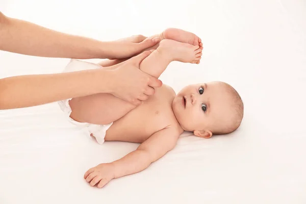 Madre y su lindo hijo en la cama blanca. Masaje y ejercicios para bebés —  Fotos de Stock