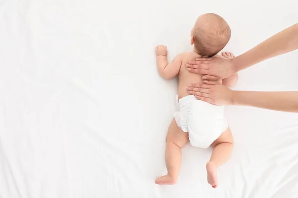 Top uitzicht van moeder en haar schattige kind op wit bed, ruimte voor tekst. Baby massage en oefeningen — Stockfoto