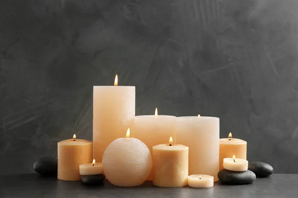 Krásné složení s osvětlenou svíčkami a lázeňskými kameny na stole — Stock fotografie