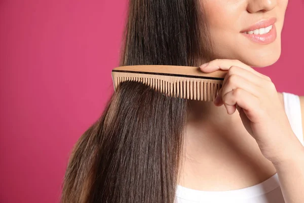 Young woman with wooden hair comb on color background, closeup. Space for text — Stock Photo, Image