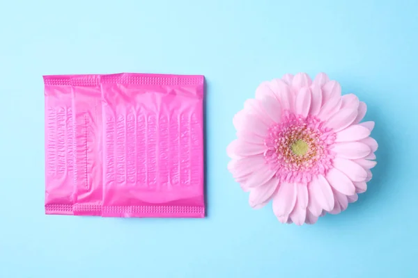 Embalado almohadillas menstruales y flores en el fondo de color, la puesta plana. Atención ginecológica — Foto de Stock
