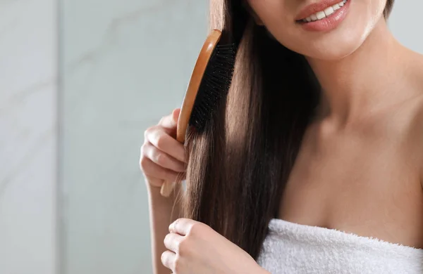 Mujer joven con cepillo de pelo en el baño, vista de cerca — Foto de Stock