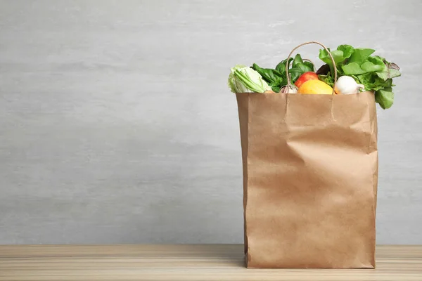 Bolsa de papel con verduras sobre la mesa sobre fondo gris. Espacio para texto — Foto de Stock