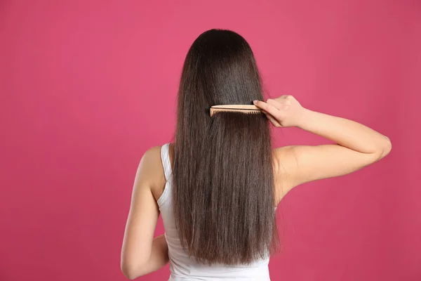 Vue arrière de la jeune femme avec peigne à cheveux sur fond de couleur — Photo