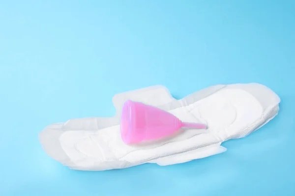 Pad dan cangkir menstruasi pada latar belakang warna. Pengobatan ginekologi — Stok Foto