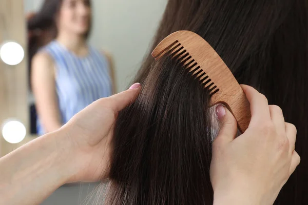 Woman combing friend's hair indoors, closeup view — Stock Photo, Image