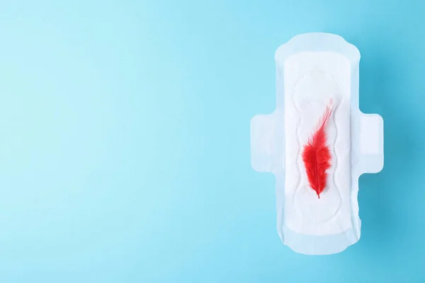 Almofada menstrual e pena vermelha no fundo de cor, vista superior com espaço para texto. Cuidados ginecológicos — Fotografia de Stock