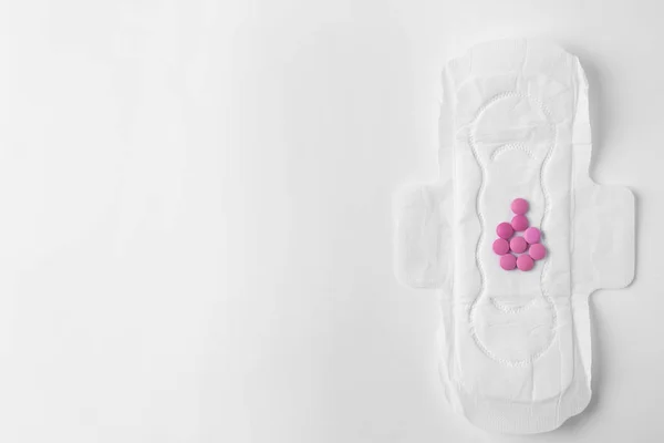 Менструальна подушка і таблетки на білому тлі, вид зверху з пробілом для тексту. гінекологічної допомоги — стокове фото
