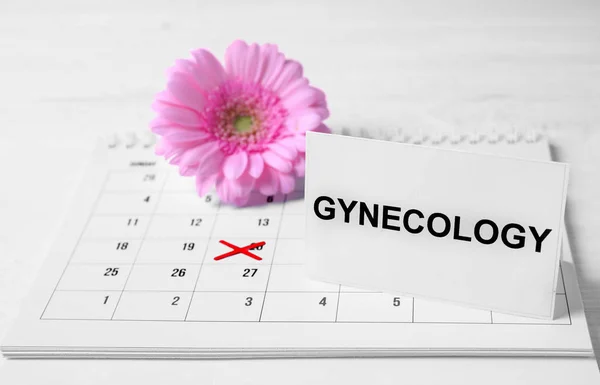 Cartão com palavra Ginecologia, calendário e flor na mesa — Fotografia de Stock