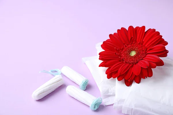 Verschiedene feminine Hygieneartikel und Blume auf farbigem Hintergrund. Gynäkologische Versorgung — Stockfoto