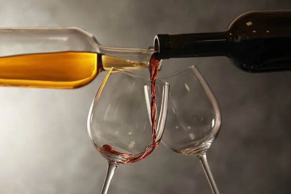 Despejar vinhos diferentes de garrafas em copos no fundo escuro — Fotografia de Stock