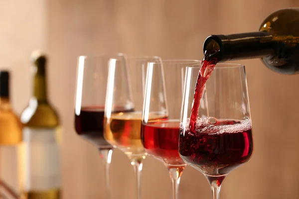 Versare il vino dalla bottiglia in vetro su fondo sfocato, primo piano — Foto Stock