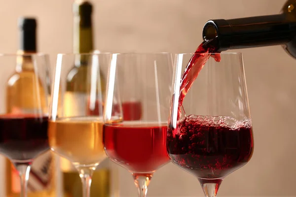 Pouring wine from bottle into glass on blurred background, closeup — Stock Photo, Image