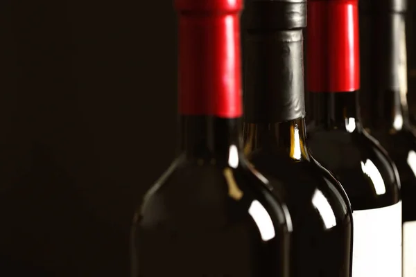 Garrafas de diferentes vinhos em fundo escuro, close-up. Recolha cara — Fotografia de Stock
