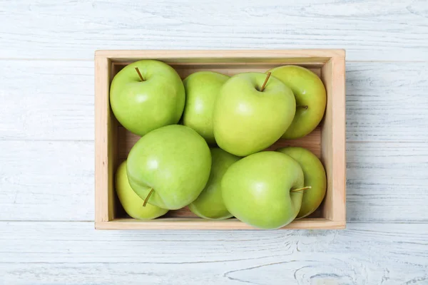 Wooden crate full of fresh green apples on light background, top view — 스톡 사진