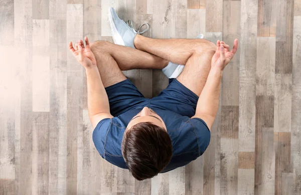 Young man sitting on floor and practicing zen yoga, top view — Stock fotografie