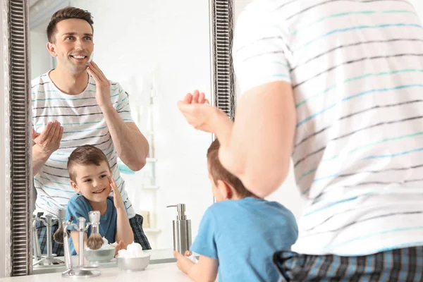 Pai de barbear e pequeno filho imitando-o no banheiro — Fotografia de Stock