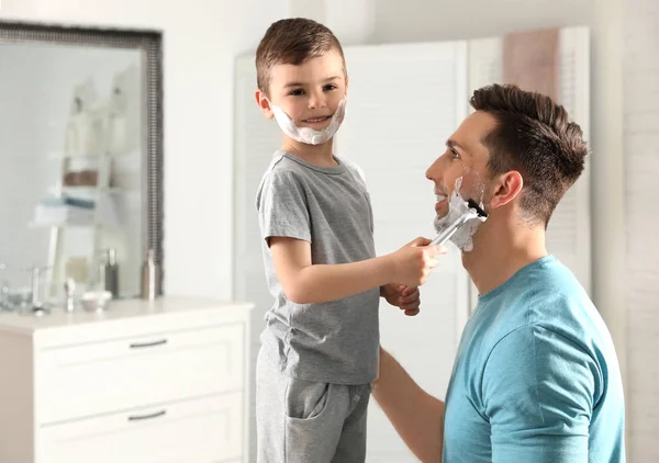 Little son shaving his dad in bathroom
