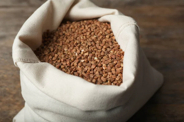 Buchweizen ungekocht im Sacktuch auf Holztisch — Stockfoto