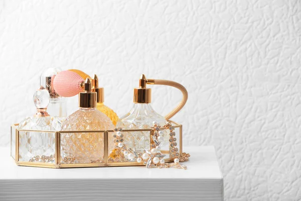 Tray with perfume bottles and jewellery on table against white background — Stock Photo, Image