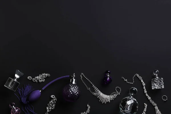 Komposition med parfymflaskor och smycken på svart bakgrund, Flat Lay. Utrymme för text — Stockfoto
