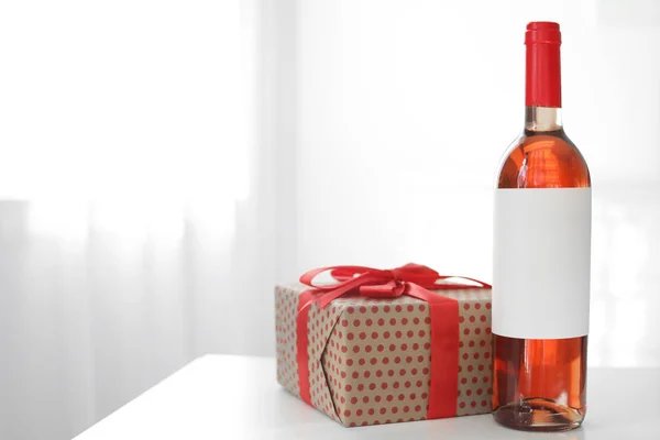 Botella de vino y caja de regalo en la mesa en la sala de luz. Espacio para texto —  Fotos de Stock